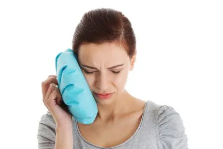 woman holding icepack to her jaw
